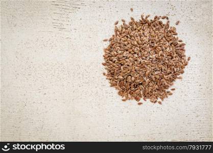 a small pile of brown flax seeds on a white painted, rustic barn wood with a copy space