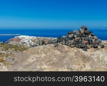 A small pyramid of volcanic rocks on the background of the village Oia on Santorini Island.. Pyramid of stones on top mountain.
