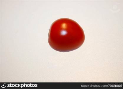 a small, red, ripe tomato (cherry tomato)