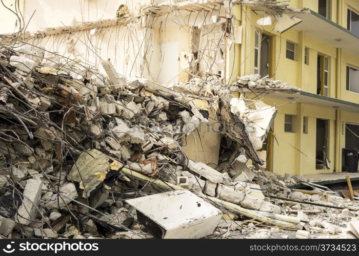 A small view of a hotel building being demolished in North Miami Beach with a pile of jumbled concrete, steel rebar, and other materials in front.