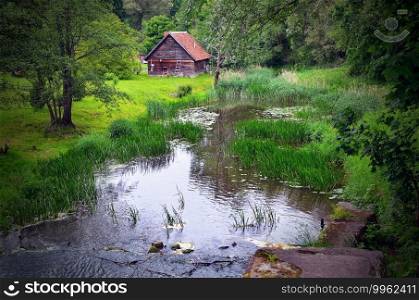 A small wooden house by the pond in the woods.. small wooden house by the pond in the woods.
