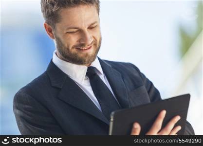A smart young businessman with a beard using a tablet computer