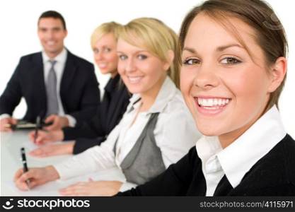 A smiling businesswoman and her three colleagues out of focus behind her taking part in a happy business meeting