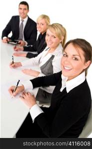 A smiling businesswoman and her three colleagues out of focus behind her taking part in a happy business meeting