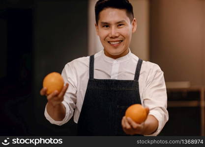 a Smiling Chef with some Oranges in Hands, Preparing for Vegan Food or Delicious Menu in a Modern Kitchen. Healthy Lifestyle Concept. Cooking At Home