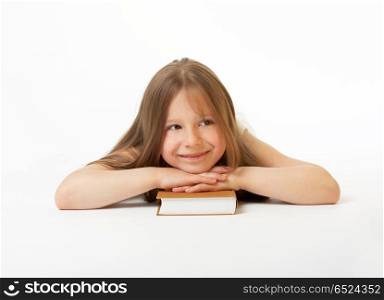 A smiling girl lays on a white background having put a head on the book. The happy clever girl