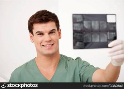 A smiling happy dentist holding x-rays, looking at the camera