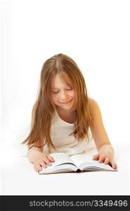 A smiling little girl lays on a white background and reads the book