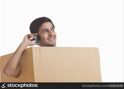 A smiling man in a box listening to music on headphones