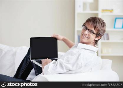 A smiling man with a laptop looks back