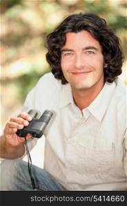 A smiling man with a pair of binoculars