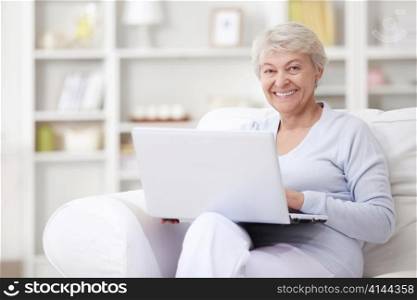A smiling middle-aged woman with a laptop at home