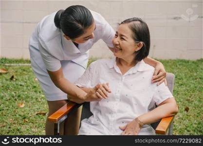 A Smiling nurse holding hands with supporting an elderly woman in a nursing house. Nursing home, Hospital, health, care, nurse Concept.