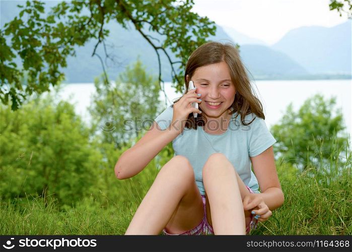 a smiling pre teenager girl calling on smartphone, outdoor