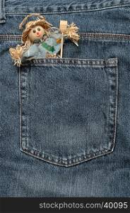 A smiling scare crow figure sticking out of the back of a denim jean