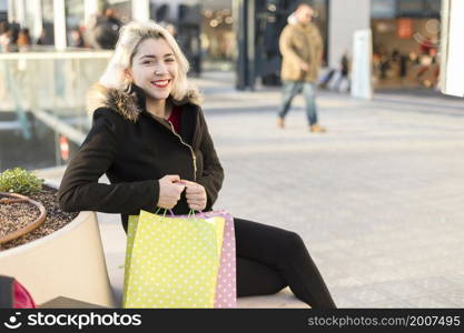A smiling shopper sitting on a street bench. Tired and smiling shopper sitting on a street bench