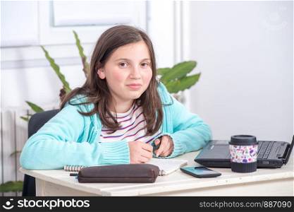 a smiling teenage girl doing homework at home