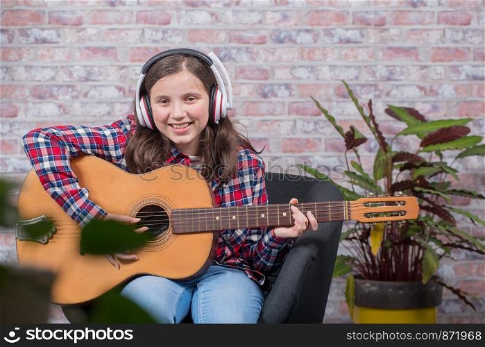 a smiling teenager girl playing an acoustic guitar