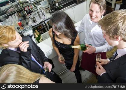 A smiling waiter, looking at the camera, whilst refilling his guest&rsquo;s glasses