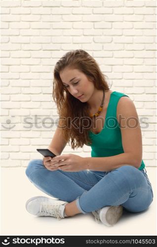 a smiling woman in green casual smart clothing, sitting crossed legs, holding smartphone