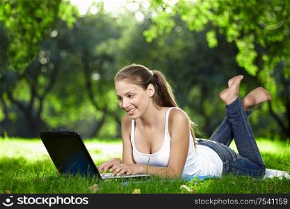 A smiling young girl with laptop outdoors