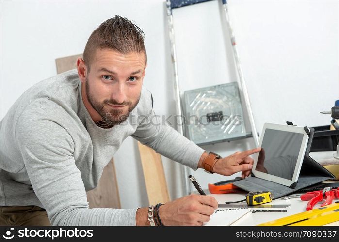 a smiling young man DIY at home with tablet