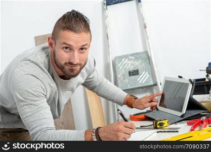 a smiling young man DIY at home with tablet