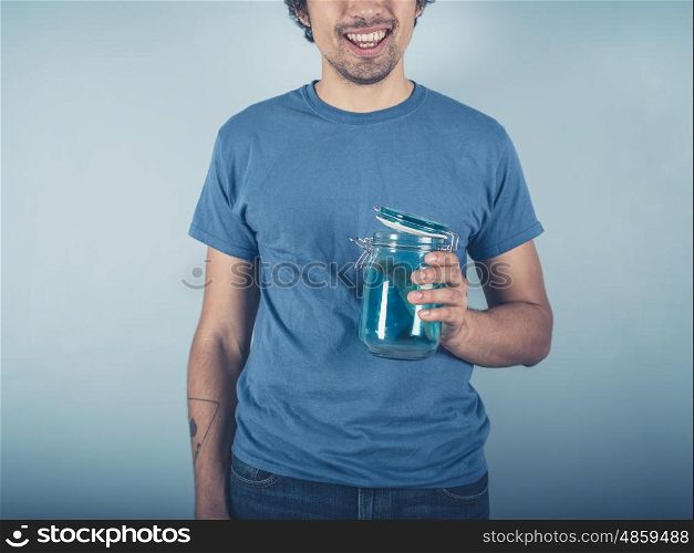A smiling young man is holding a jam jar