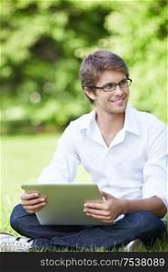 A smiling young man with laptop outdoor