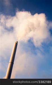 A smoke stack polluting into a blue sky