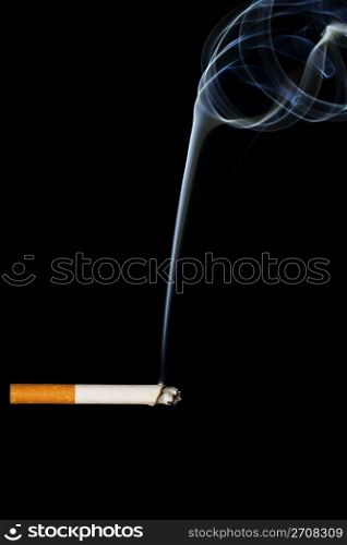 a smoking cigarette. a smoking cigarette in front of black background
