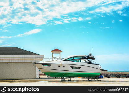 a snow white yacht stands on a pier on coasters on a Sunny day against a beautiful sky with clouds