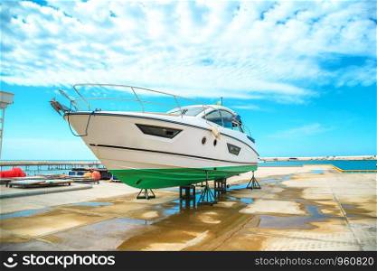 a snow white yacht stands on a pier on coasters on a Sunny day against a beautiful sky with clouds