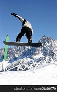 A snowboarder jumping freestyle in the mountains