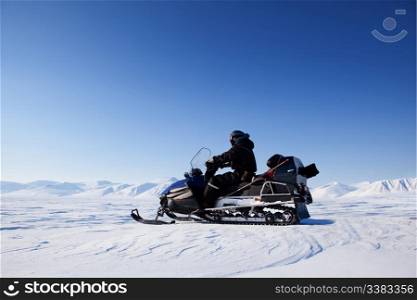A snowmobile on a frozen lake against a winter landscape with mountains