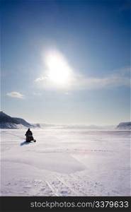 A snowmobile on frozen ice on a barren winter landscape