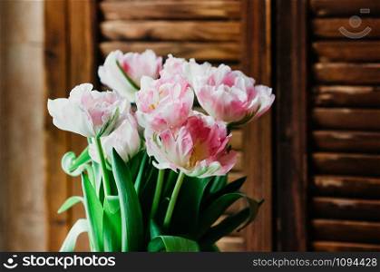 A soft focused bouquet of pink flowers, wooden jalousie in the background, rustic style, closeup view, indoors