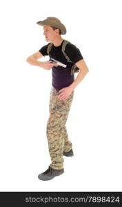 A soldier in camouflage pants, hat and black t-shirt pulling his hand gunout of the holster, isolated on white background.