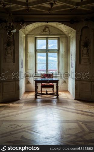 A solitaire chair and table in an ampty room of Castle Savoia, building in typical Walsen architectural style.