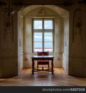 A solitaire chair and table in an ampty room of Castle Savoia, building in typical Walsen architectural style.