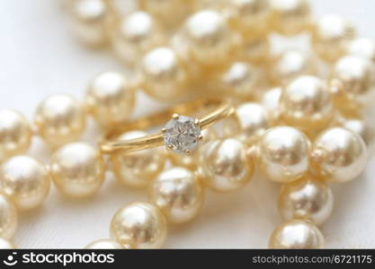 A solitaire diamond engagment ring on a pearl necklace