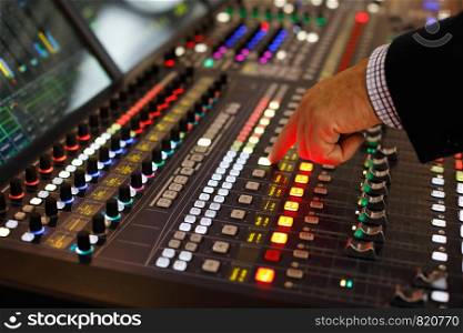 A sound engineer at the controls of an audio production console. Selective focus.