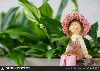 a souvenir statuette of a girl sitting on a background of foliage. souvenir statuettes of a girl