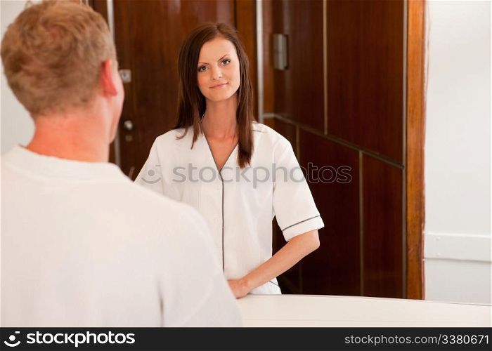 A spa receptionist greeting a male customer at the welcome desk