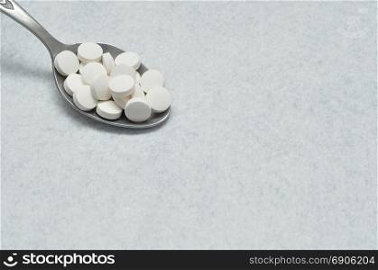 A spoon filled with white tablets