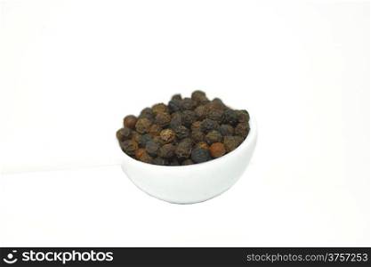 A spoon of black pepper isolated on white background