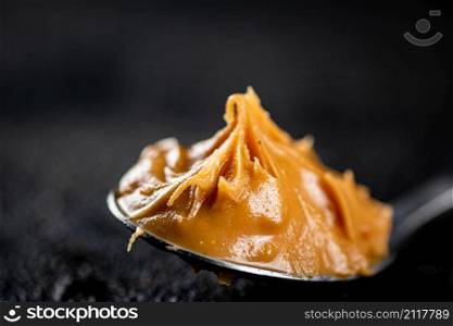 A spoonful full of peanut butter. On a black background. High quality photo. A spoonful full of peanut butter.