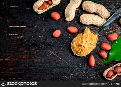 A spoonful of peanut butter on a table with leaves. On a rustic dark background. High quality photo. A spoonful of peanut butter on a table with leaves.