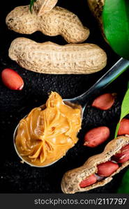 A spoonful of peanut butter on a table with leaves. On a rustic dark background. High quality photo. A spoonful of peanut butter on a table with leaves.