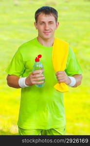 a sportsman holding bottle of water and looking at camera